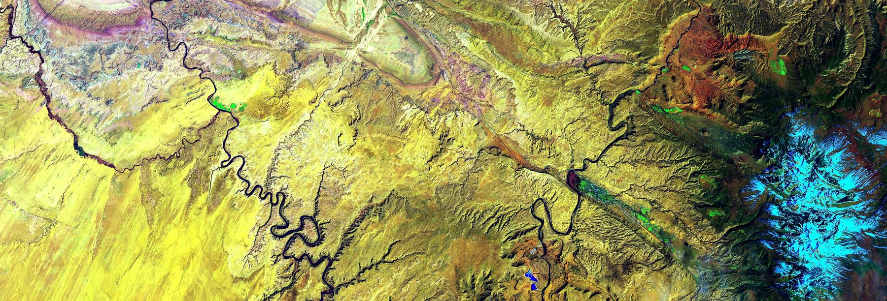 False-color aerial image of a meandering river across yellow farmland.