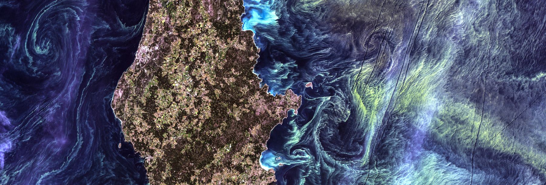 False-color aerial image of ocean currents swirling around a dark island.